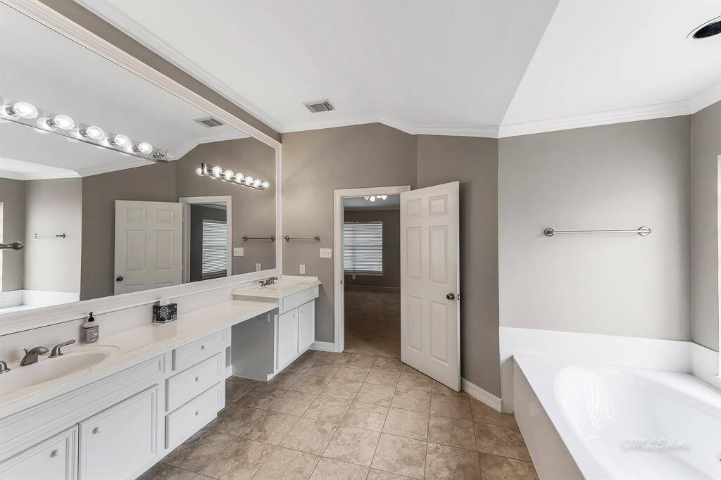 Alternate view of the master bathroom highlights the storage capacity in the dual vanities.