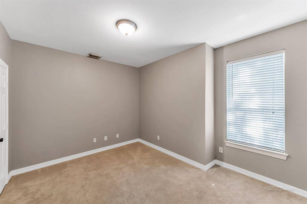 Secondary bedroom located on the first floor features carpet, bright window and walk in closet.