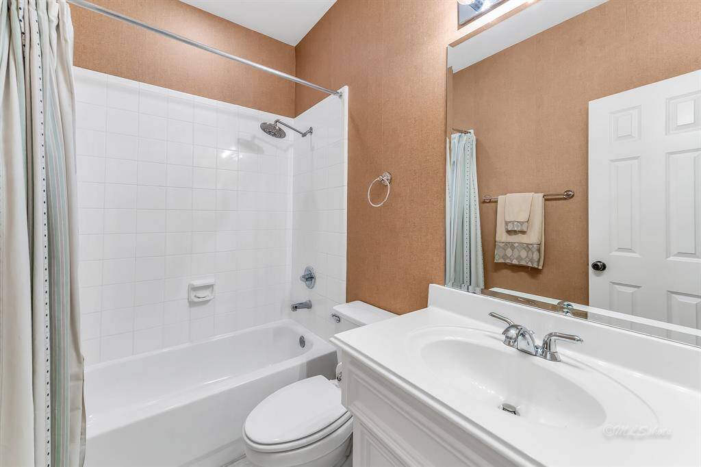The full bath features decorator paint, tile floor, a rain showerhead, studio lighting, and nickel finish hardware. This full bath is located on the first floor to accompany the secondary bedrooms.