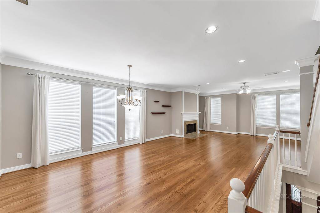 Stunning dining and living room featuring hardwood floors, 5" baseboard trim, gas fireplace, recessed lighting, lots of windows for natural light, lovely banister that continues the open concept design.