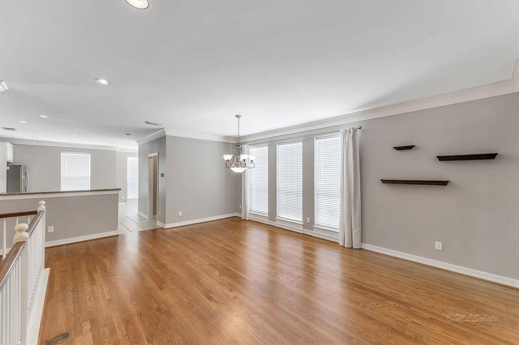 The dining room features crown molding, a beautiful chandelier, and bright windows. It will accommodate a dining table to serve 8-10 and flows to the kitchen for easy entertaining.