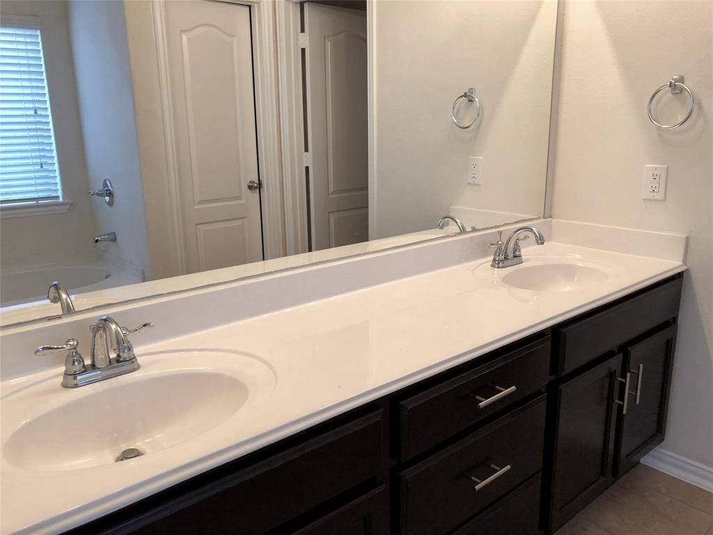 Modern primary bathroom with double sinks and spacious walk in closet.