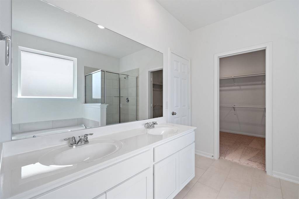 The en-suite bathroom offers a spa-like atmosphere with its elegant design, high end finishes, and tasteful lighting, creating a retreat within your own home.