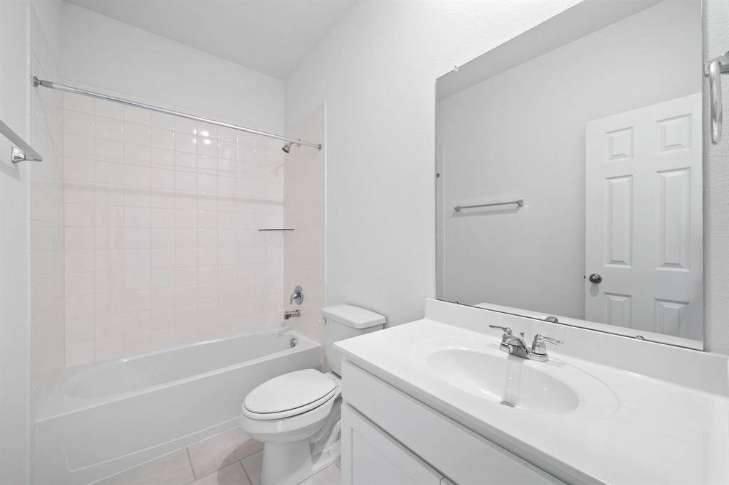 The secondary bath features tile flooring, white cabinetry and light countertops and a shower/tub combo. Perfect for accommodating any visiting family and friends.