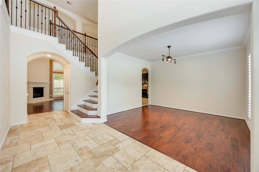 From the entryway, enjoy this artistic view that features high ceilings, arched entryways, and a gorgeous wooden staircase.