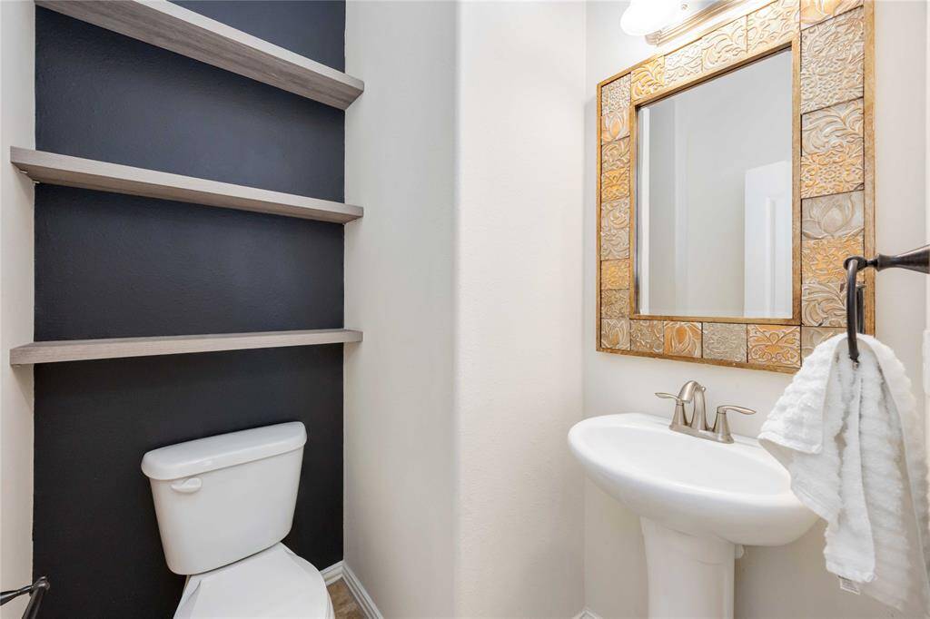 A convenient half bath on the first floor offers a pedestal sink under a stylish framed mirror.