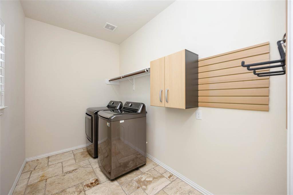 A large indoor utility space features cabinets and extra space for storage. The washer and dryer are included with the rental.