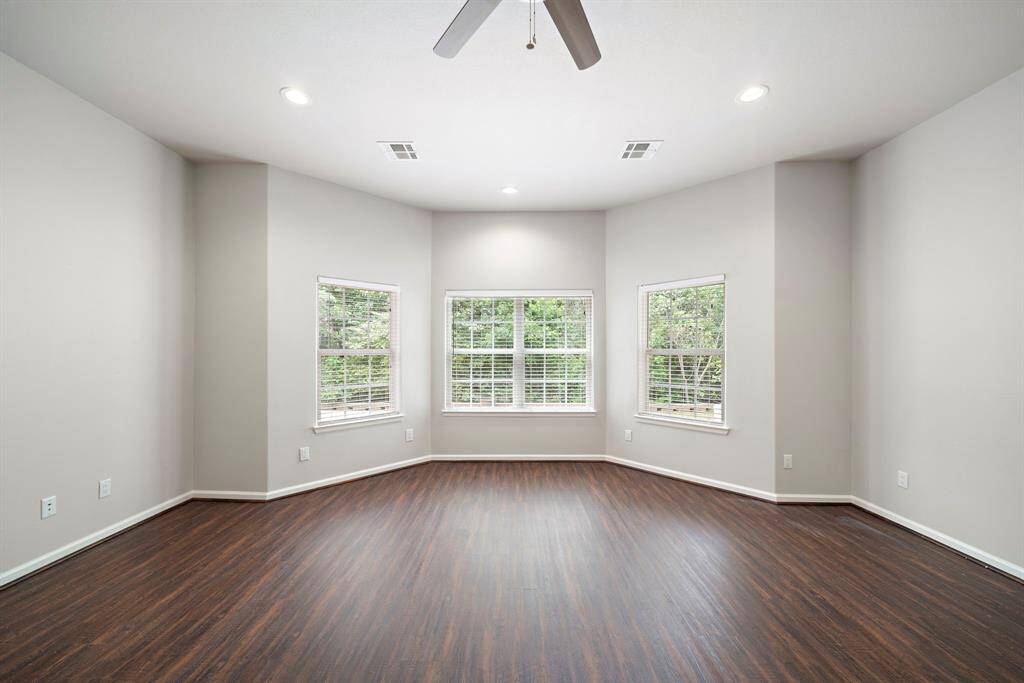 Serene primary bedroom sanctuary in a 2017 custom-built home in Panorama Village, perfect for homebuyers seeking a peaceful retreat with a golf enthusiast’s lifestyle. This expansive space boasts brand new luxury vinyl plank flooring, adding a touch of modern elegance, while large windows flood the room with natural light and offer tranquil views of the greenery outside. The spacious layout provides ample room for relaxation or personalization.