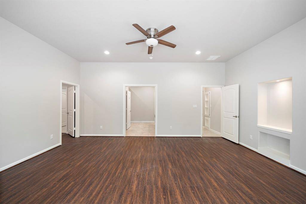 Luxurious primary bedroom retreat in a 2017 custom-built home in Panorama Village, designed for homebuyers seeking comfort and style with a golfer’s lifestyle. This second view highlights the seamless flow into the ensuite bathroom, offering a private oasis with ample space and modern finishes. The brand new luxury vinyl plank flooring adds a sleek, contemporary touch, while the spacious layout provides versatility for relaxation.This primary suite is your perfect chip shot to luxury living!