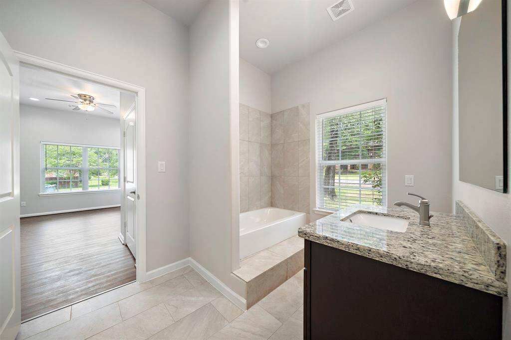 Connecting the two secondary bedrooms is a thoughtfully designed Jack and Jill bathroom—perfect for accommodating guests or family with ease and privacy. Featuring a sleek granite countertop, elegant tile flooring, and a combination tub and stand-up shower, this bathroom offers both functionality and modern style. A large window provides soothing natural light while maintaining a sense of retreat and relaxation.This space is ideal for those who appreciate comfort and convenience—whether freshening up af