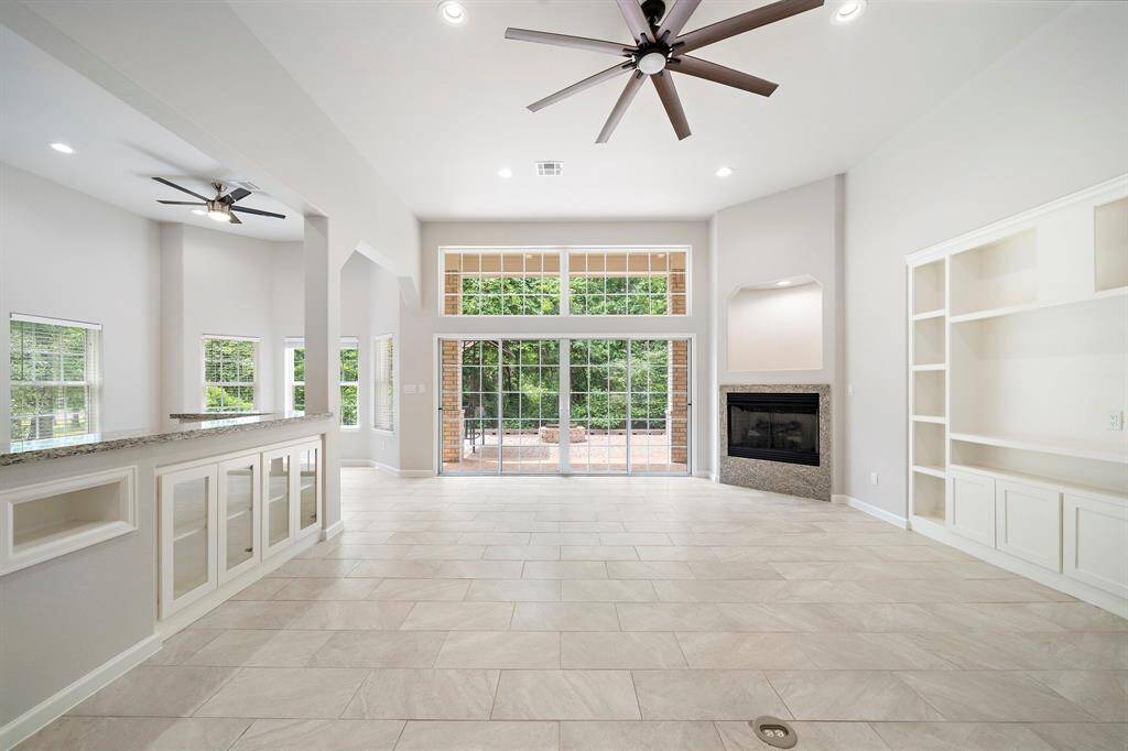 This inviting space features custom built-ins, a cozy fireplace, and a large sliding door that opens to the backyard, creating a seamless indoor-outdoor flow with views of the serene greenery. Perfect for relaxing or entertaining, the room’s airy design and recessed lighting elevate its charm. Situated on the Panorama Golf Course, this home offers direct access to the fairways, while Lake Conroe is just a short drive away for boating adventures.
