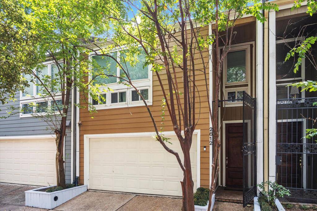 Discover the charm of 2612 Yupon St, a serene townhome nestled among lush greenery with a welcoming entrance and private garage.