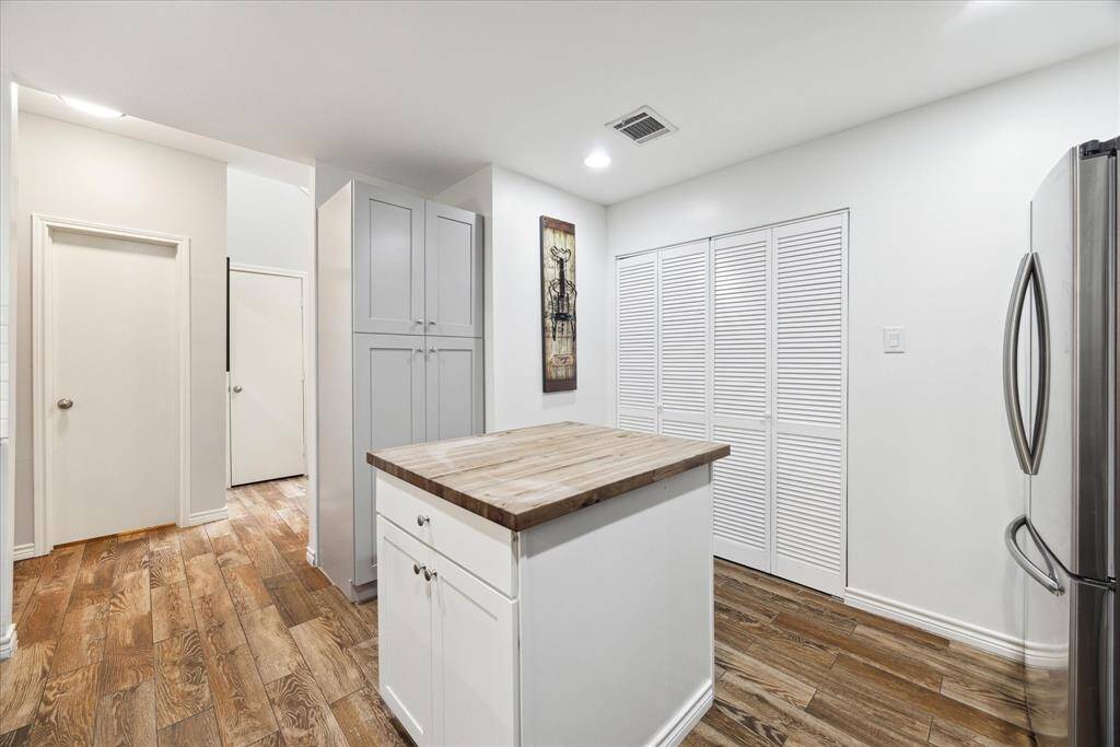 Experience the elegance of this modern kitchen featuring a versatile island, ample built-in pantry space, and concealed washer/dryer for a sleek, clutter-free environment.