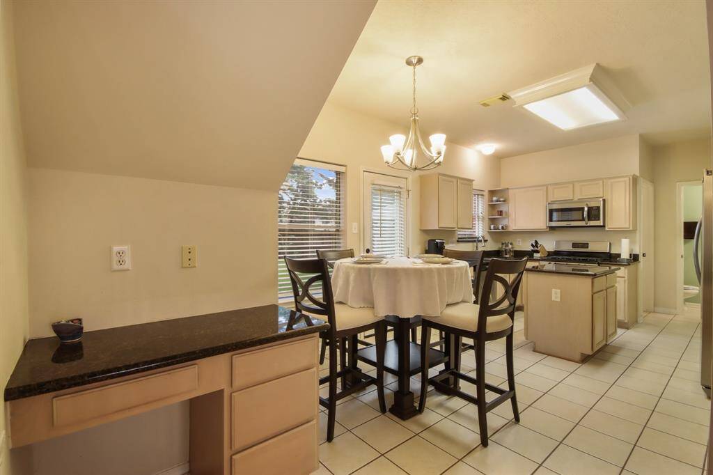 This bright kitchen features modern appliances, and a central island with a gas stove and a cozy breakfast area. The space also includes a small desk area, perfect for multitasking or additional storage.