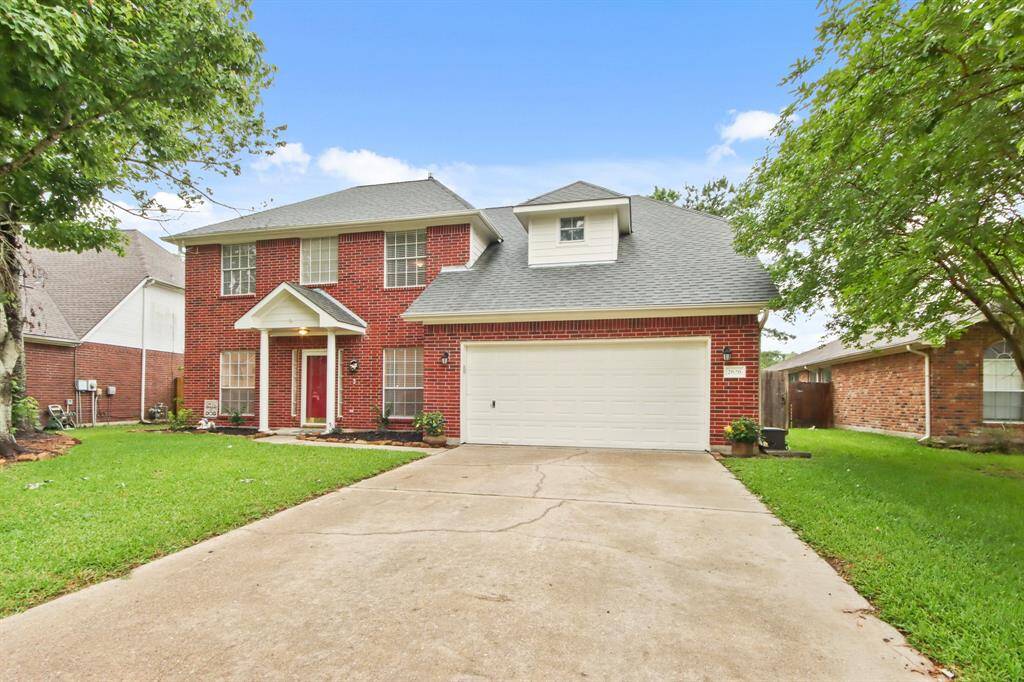 This charming two-story brick home features a spacious driveway leading to a two-car garage. It’s surrounded by a well-maintained lawn with mature trees, offering great curb appeal.