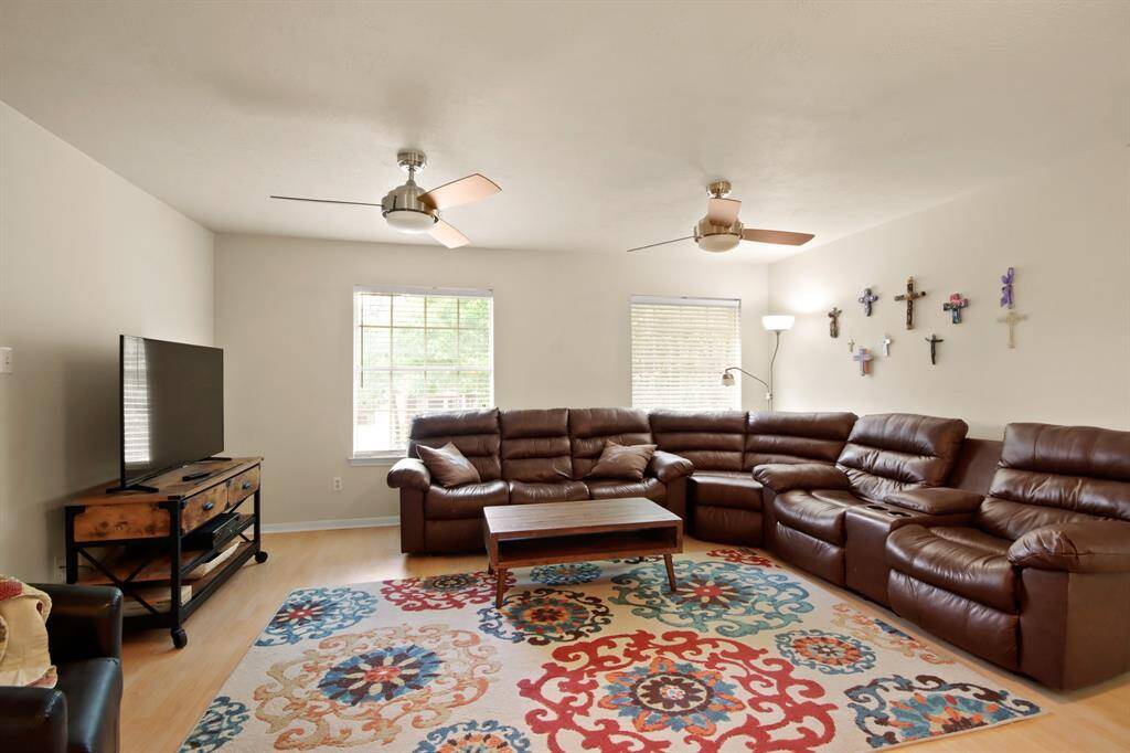 Bright and spacious second floor living room with large windows right up the stairs features modern ceiling fans and is a great gathering space.