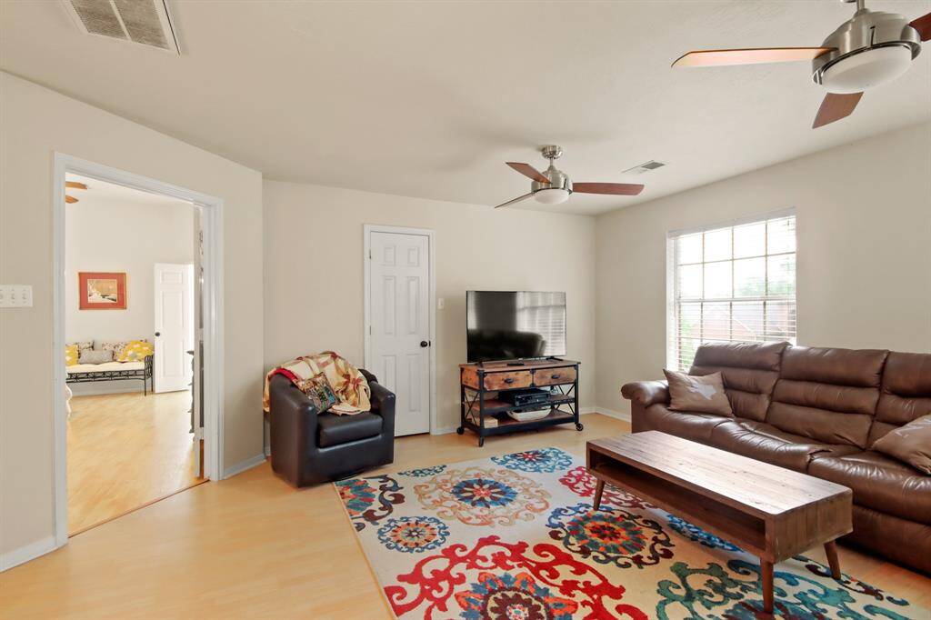 This cozy second floor living room has ample natural light from a large window, two modern ceiling fans, and photo shows entryway leading to primary bedroom.