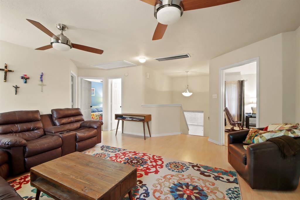 Photo shows the second floor living space with two fans. It offers an open layout with natural light, leading to multiple rooms for versatile use.