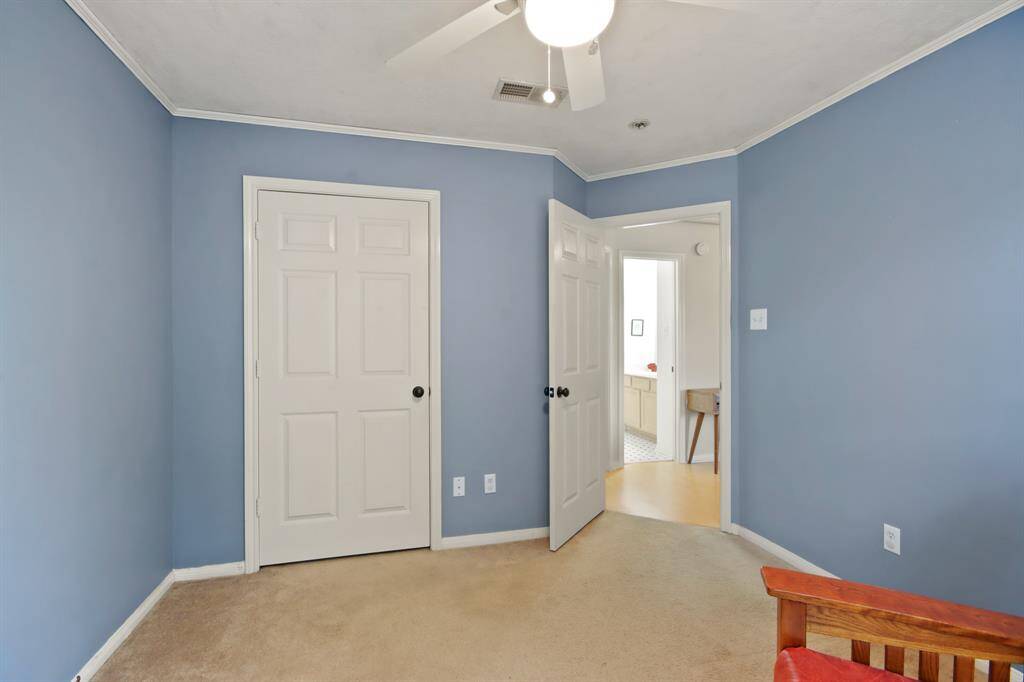 This bedroom features blue walls and a ceiling fan with a light fixture. It has two white doors with one leading to a closet and the other leading out into the second floor living area.