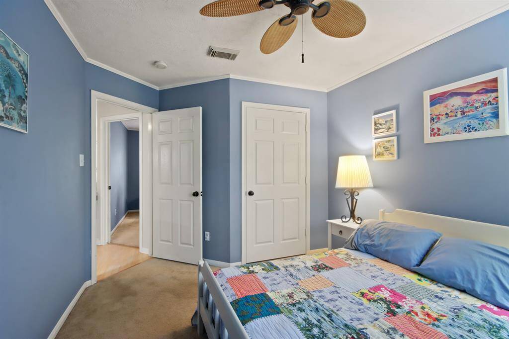 This cozy bedroom features a ceiling fan with leaf-shaped blade.  Bedrooms closet and entryway leads to second floor living area.