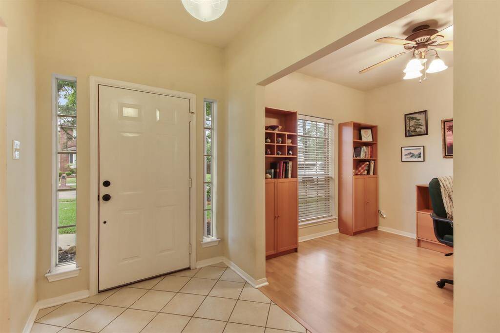 This inviting entryway features a tiled floor leading to an adjacent cozy office space with wooden flooring and a ceiling fan, offering a warm and functional first impression.