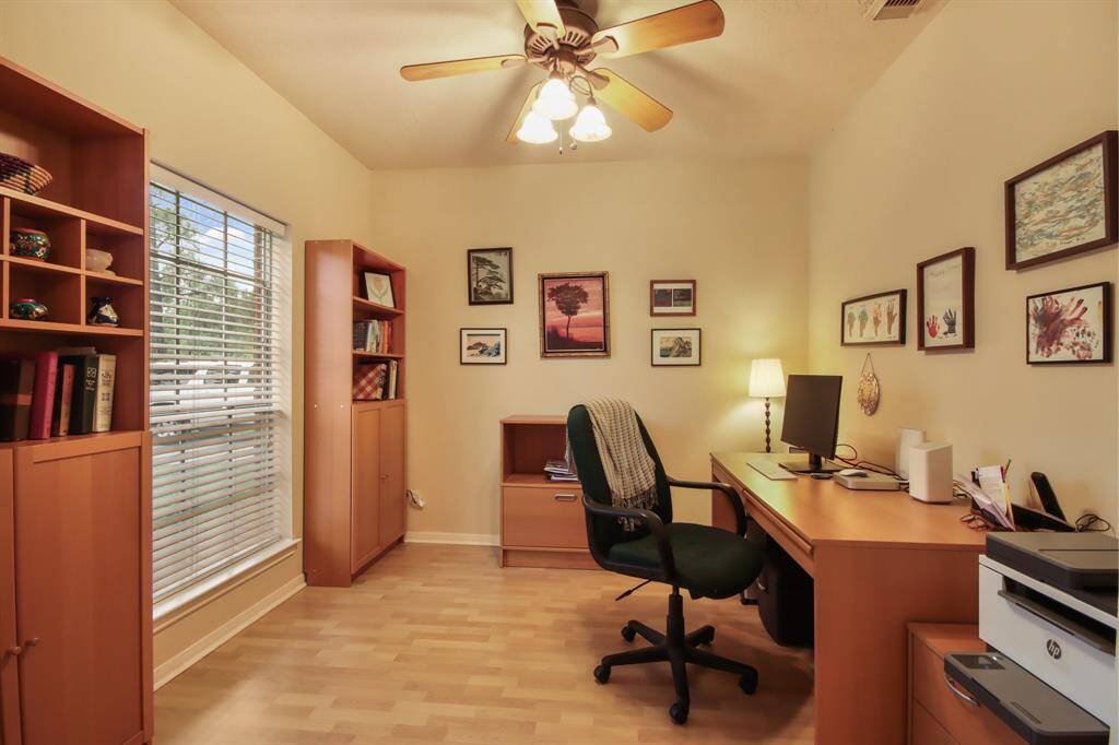 This cozy home office features a large window for natural light, and a ceiling fan. When entering the home it is to the left of the front door.