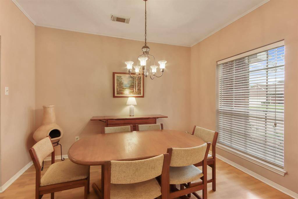 This dining room features window with blinds allowing natural light to fill the space and view of the front yard. A charming chandelier hangs above the space.
