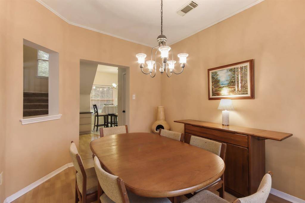 This cozy dining room features  a chandelier with an entrance way that leads to the kitchen. An opening allows viewing of the living area.
