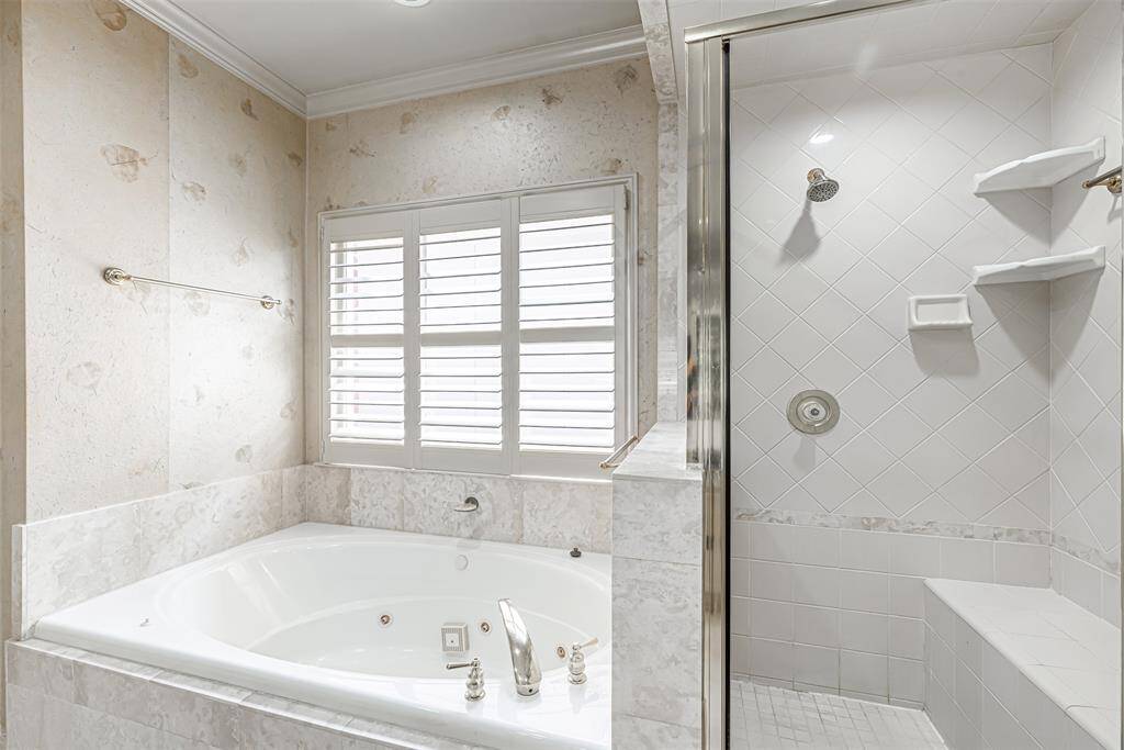 Neutral tile surround for this whirlpool tub including shutters over window and separate stand up shower with seat.
