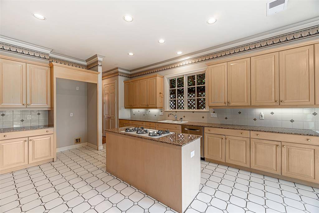 Kitchen has canned and under cabinet lighting as well as an island with gas cooktop. The kitchen also has a butler's pantry and double door pantry.