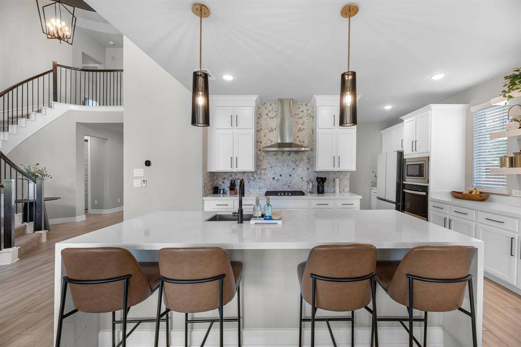 View of the kitchen featuring the quartz waterfall island and winding staircase in the backround.