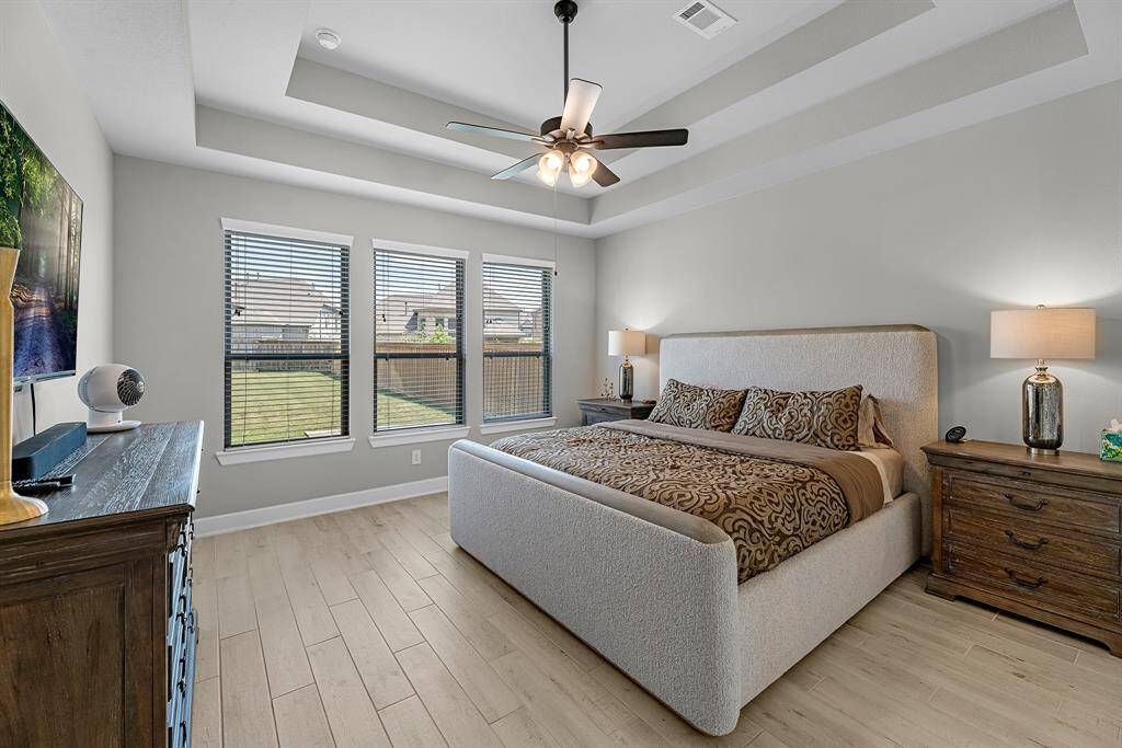 Primary bedroom retreat featuring tray ceilings and tranquil backyard views.