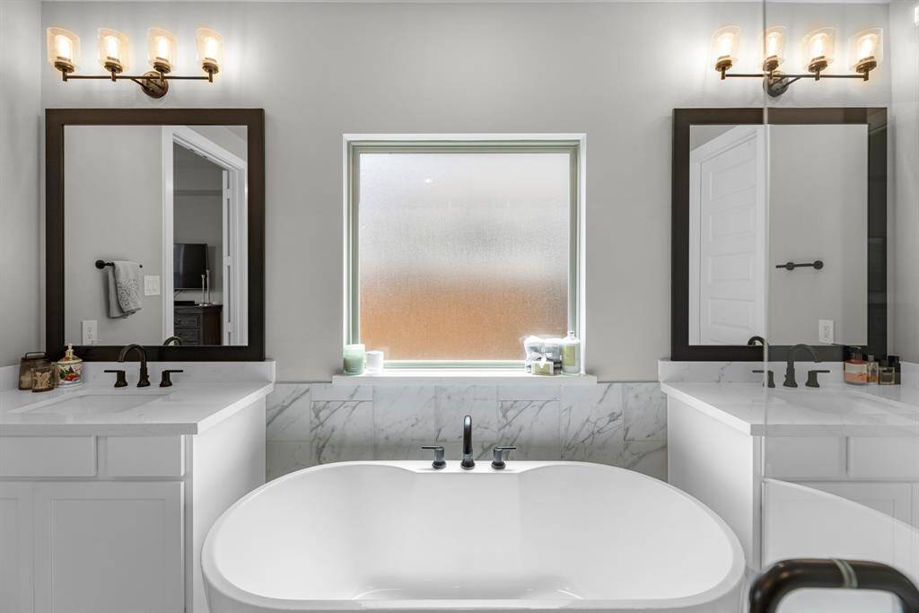 Additional view of the double sinks and soaking tub in the primary bathroom.
