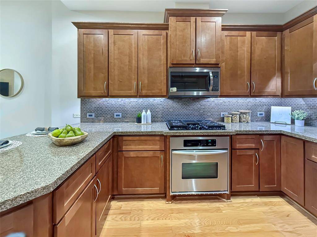 Light and bright kitchen with granite counters, stainless steel appliances, recessed lighting, under cabinet lighting, stained wood cabinetry and contrasting stone back splash. Appliances include dishwasher, microwave, gas cook top, electric oven and full size refrigerator.