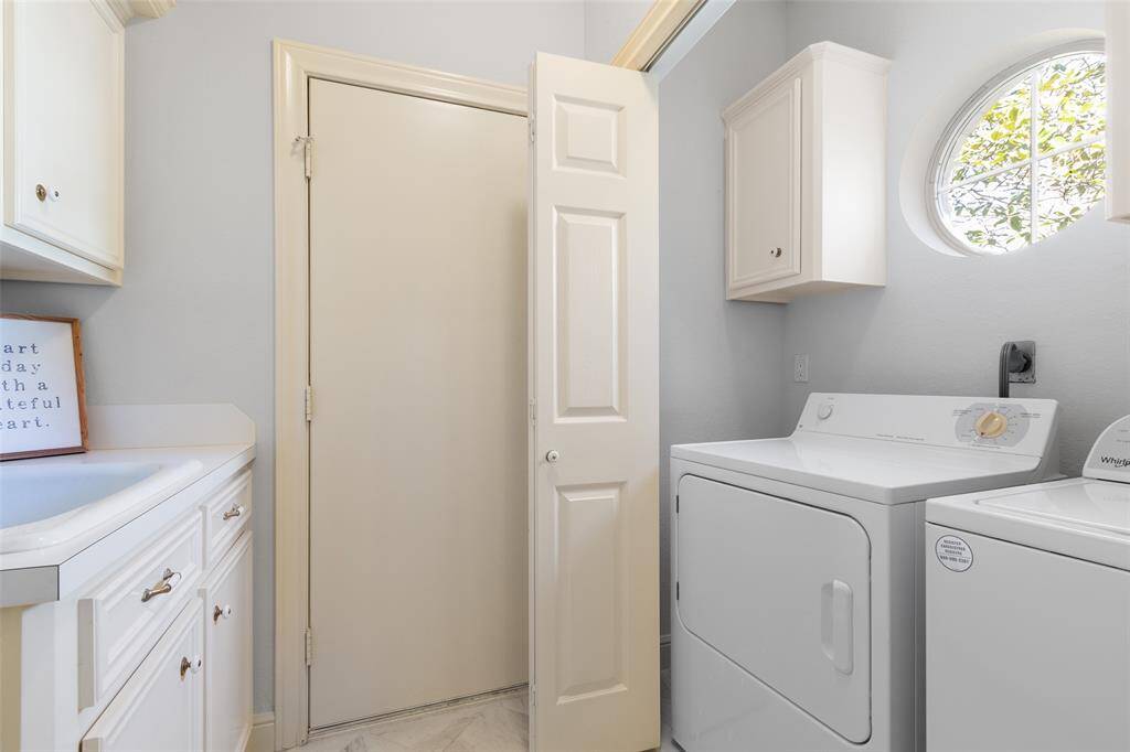 Light-filled laundry room has the most adorable octogon window overlooking the front yard. This well-designed space is both functional and pretty.
