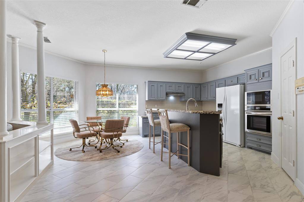 Cheerful and bright breakfast room is adjacent to the kitchen with breakfast bar. Custom built shelves on left side "buffet" area are welcomed storage.