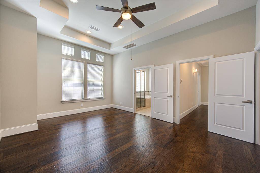 The primary bedroom, located on the third floor, boasts a high tray ceiling, the hickory wood floors and a great sitting area.
