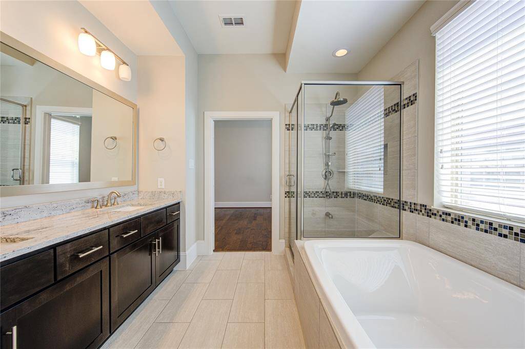 The oversized shower features a rainforest shower head above and a removable hand sprayer.