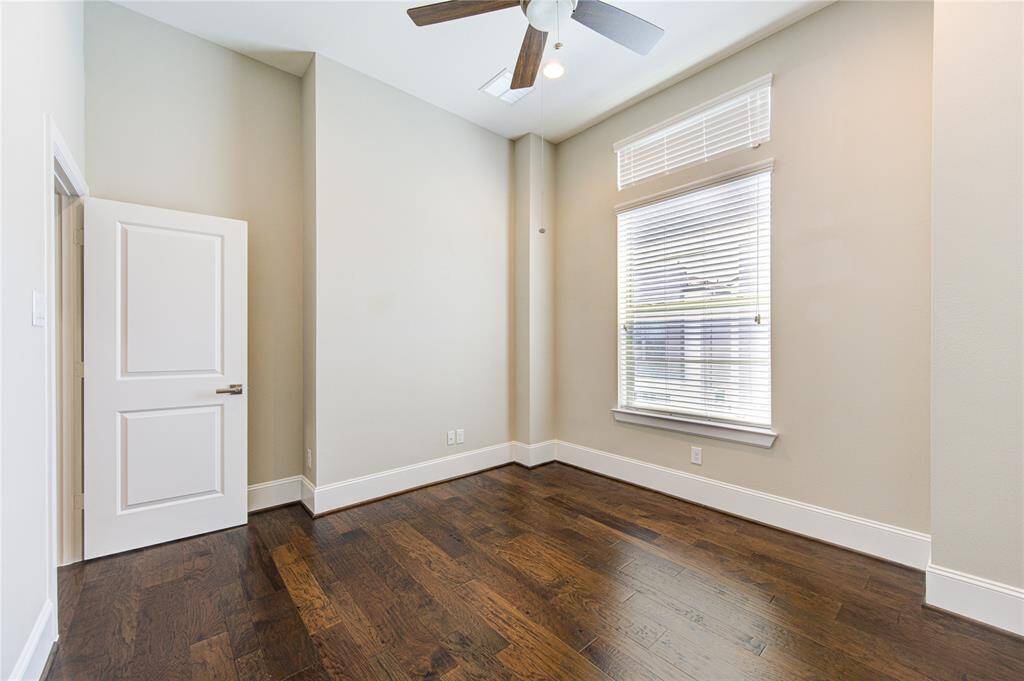 The secondary bedroom on the third floor features a high ceiling, ceiling fan and the wood floors.
