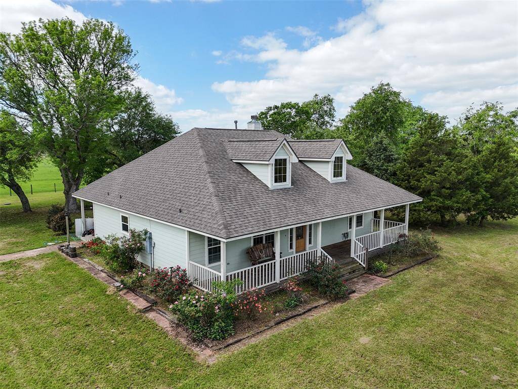 This charming home features a wide front porch with classic dormer windows and lush landscaping—perfect for enjoying quiet mornings or evening breezes.