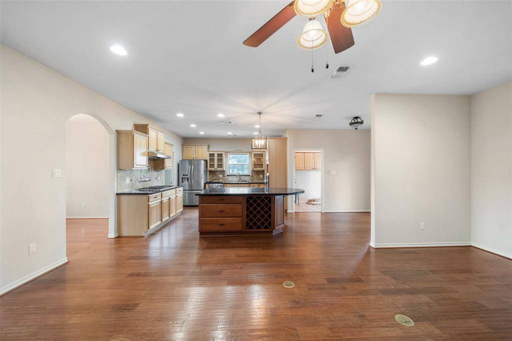 Ample cabinetry, a gas cooktop, and a tile backsplash with decorative accents combine functionality with visual interest in this well-appointed kitchen.