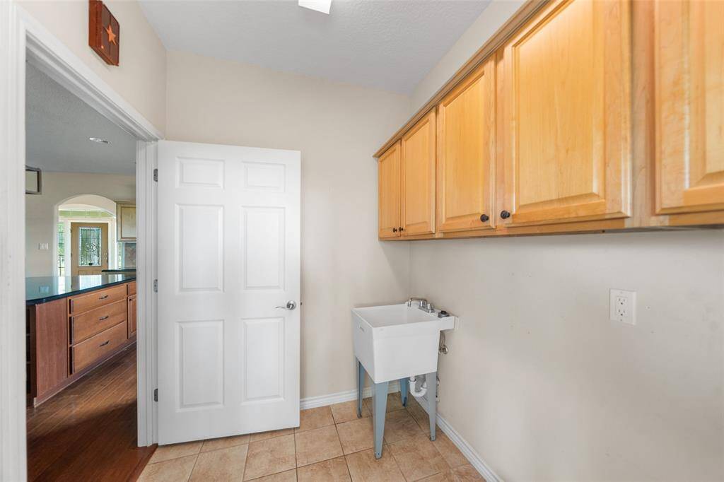 The utility room includes upper cabinetry for extra storage and a utility sink—ideal for cleanup after outdoor projects.