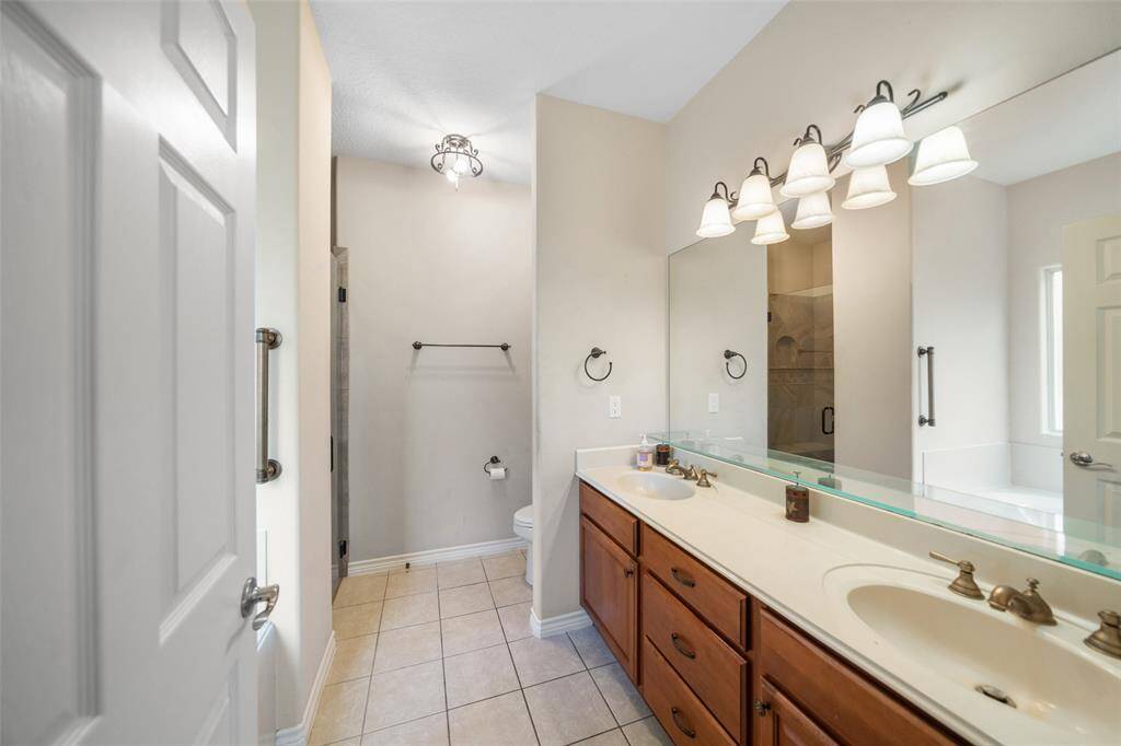 Enjoy the convenience of a dual vanity setup in the primary bathroom, along with plenty of storage and a large mirror to brighten the space.