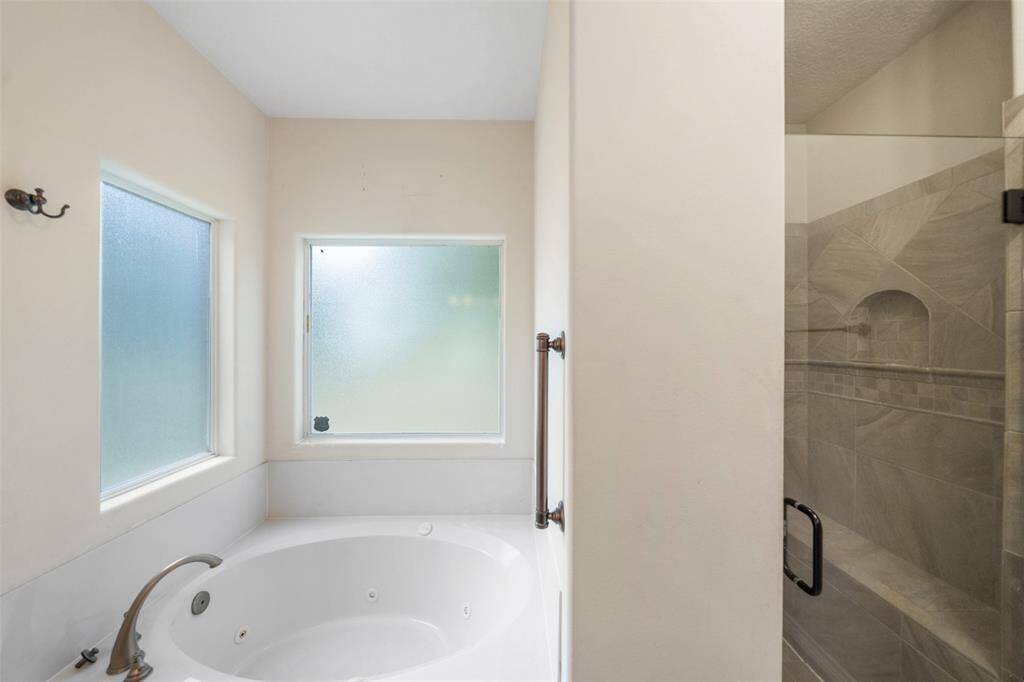 The primary bath includes a soaking tub nestled between frosted windows, creating a light-filled retreat with added privacy.