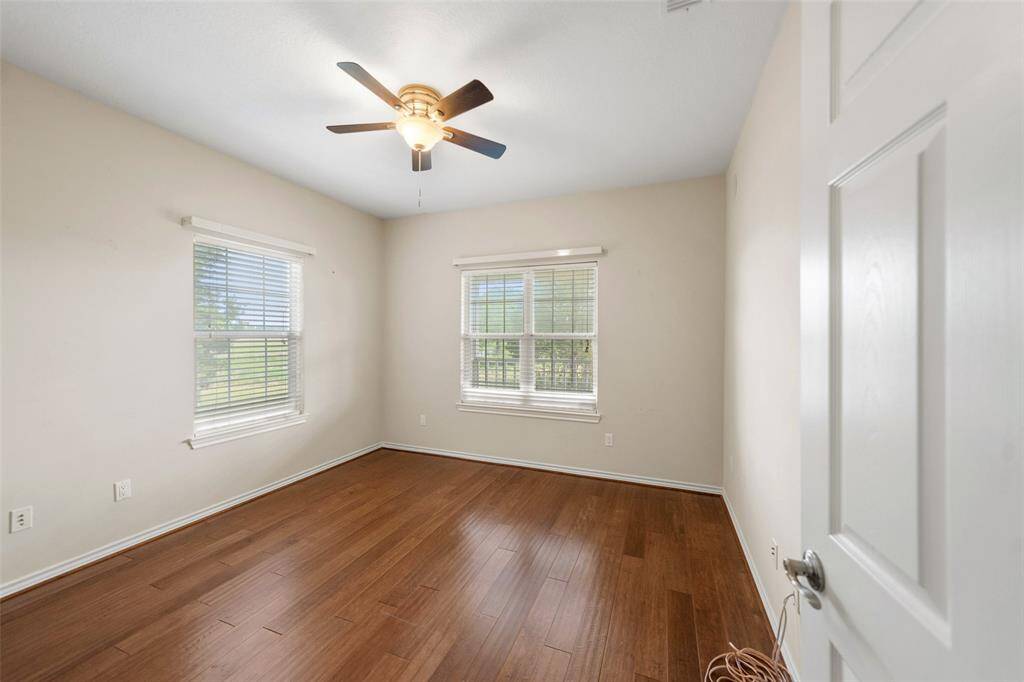 One of the secondary bedrooms offers wood flooring, dual windows for great light, and a ceiling fan for comfort year-round.