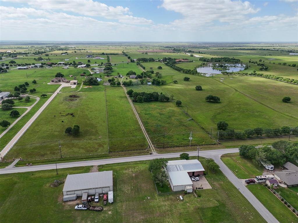Sweeping aerial view showcases the expansive acreage and ideal layout with multiple fenced sections and structures in place.