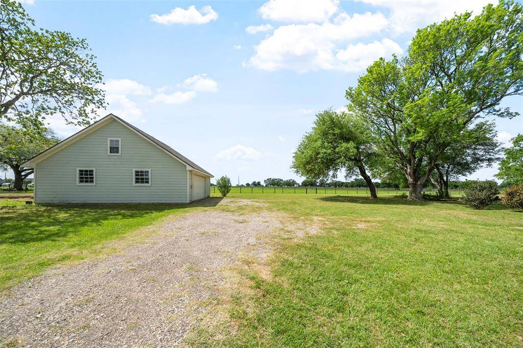 The detached garage with finished upstairs space offers flexible storage or bonus area, framed by shady mature trees.