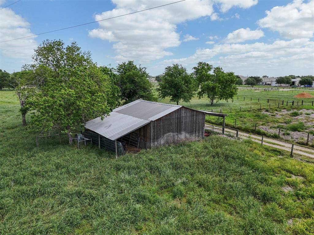 Classic weathered barn structure provides rustic charm and functionality with nearby fenced pastures and road access.