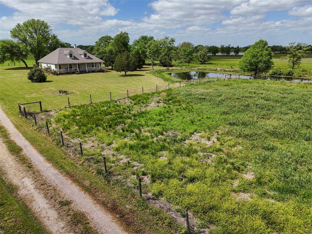 Backyard view of the home shows proximity to the pond, highlighting both privacy and picturesque surroundings.