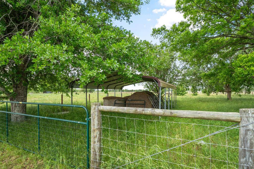 Well-shaded, fenced-in area with hay barn—functional for livestock, feed storage, or additional rural uses.